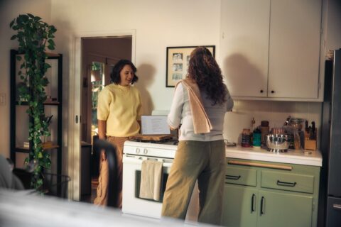 Two women talking in a kitchen while cooking