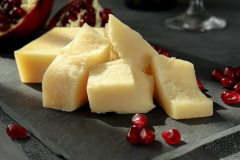 sliced cheese on black plate beside wine glass