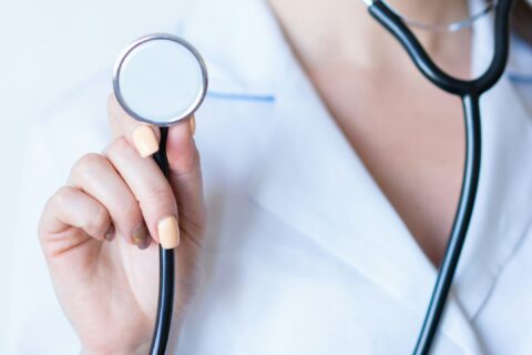 a woman in a white shirt holding a stethoscope