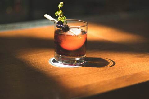 brown beverage with olives and herb in rocks glass in macro photography