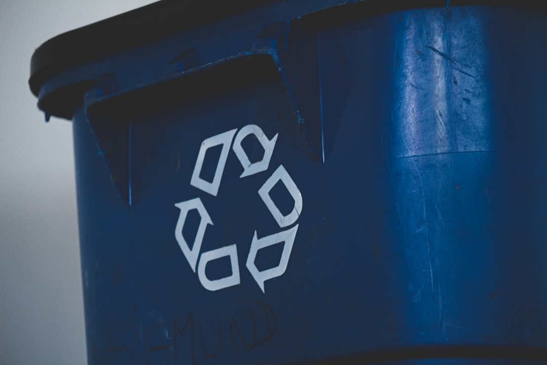 A white recycling symbol on the side of a blue plastic bin