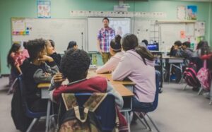 students in classroom with teacher presenting